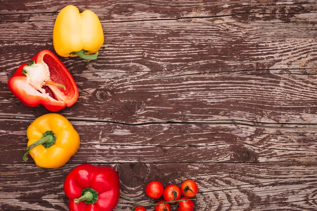 Roter und gelber grüner Pfeffer und Kirschtomaten über dem hölzernen Schreibtisch