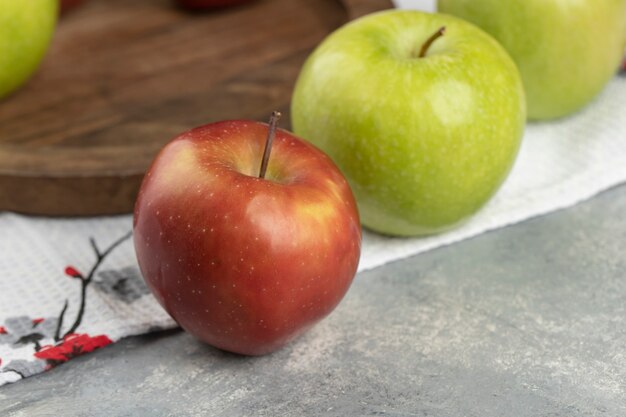 Roter und grüner frischer Apfel, der um Holzteller gelegt wird.