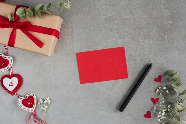Rotes Blatt in der Nähe von Geschenk, Stift, Ornament Herzen und Pflanzen