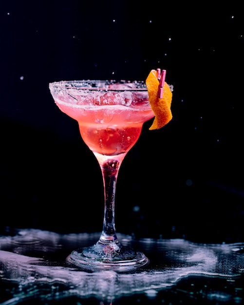 Rotes Cocktail mit abgezogener Orangenhaut und gehackten Eiswürfeln.