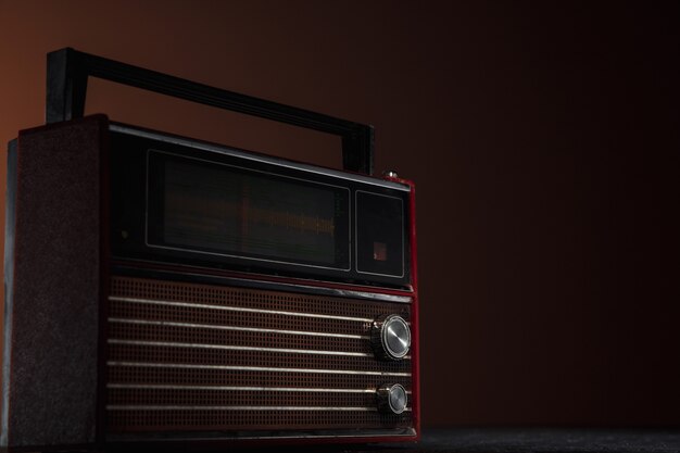 Rotes Radio auf dunklem Hintergrund. Nahaufnahme von alten Retro-Dingen, die mit Farben im Vintage-Stil geschossen und getönt wurden.