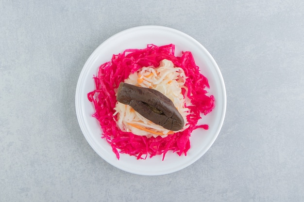 Rotes und weißes sauerkraut mit auberginen auf weißem teller.