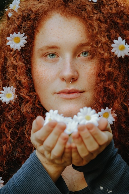 rothaarige Frau, die Gänseblümchenblumen hält