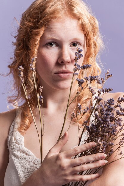Rothaarige Frau posiert, während sie einen Strauß Lavendel hält