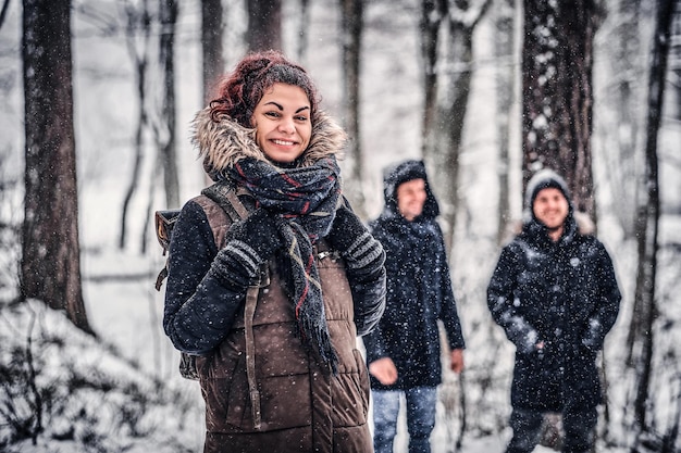 Rothaarige Studentin reist mit Freunden in den verschneiten Wald