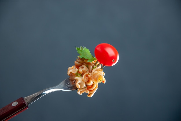 Rotini-Nudeln der Vorderansicht mit Kirschtomate auf Gabel auf grauem isoliertem Oberflächenkopierraum