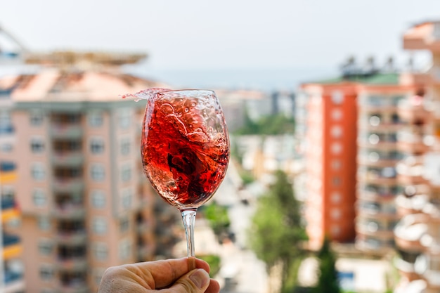 Rotwein mit Eiswürfeln in einem Glas auf einer Außenansicht. Seitenansicht.