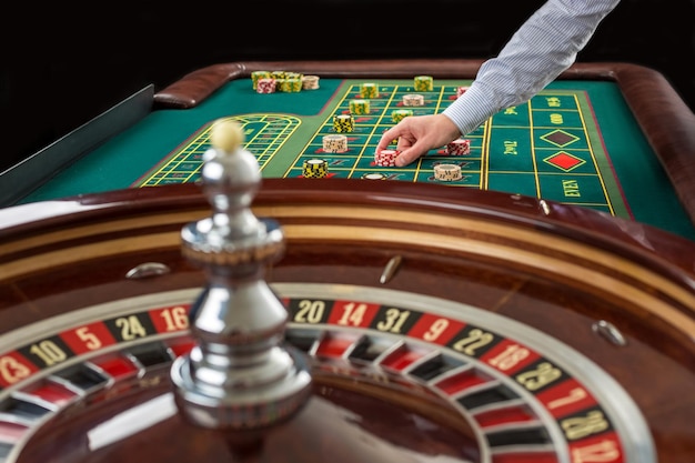 Roulette und Stapel von Glücksspielchips auf einem grünen Tisch im Casino.