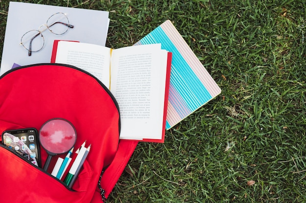 Rucksack mit Briefpapiermaterial auf grünem Gras