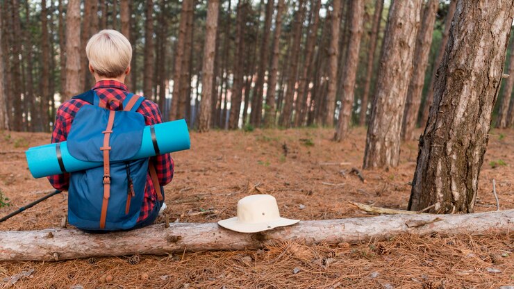 Kostenlose Foto rückansicht der älteren touristenfrau im wald mit rucksack