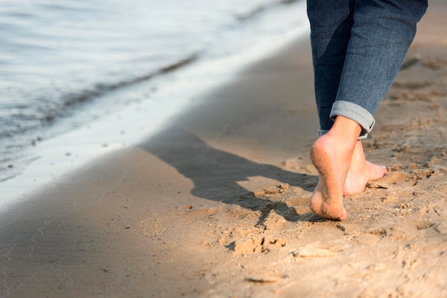 Rückansicht der Frau, die barfuß auf dem Strand geht