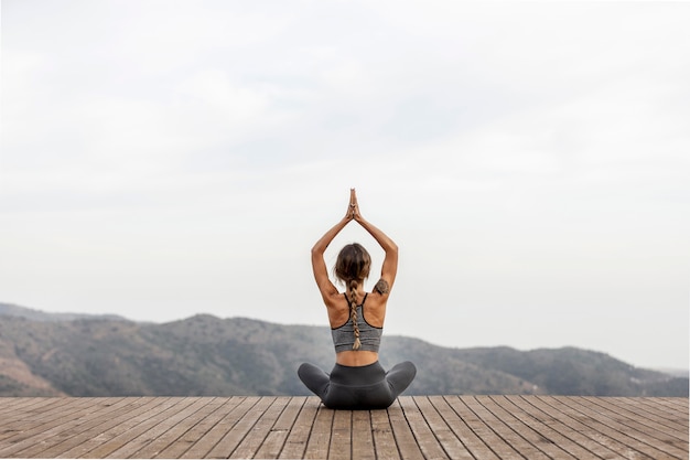 Rückansicht der Frau, die Yoga im Freien tut