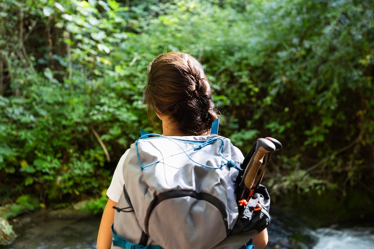 Kostenlose Foto rückansicht der frau mit rucksack, der natur erforscht