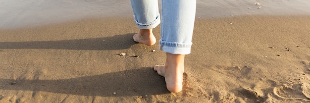 Rückansicht der Frauenfüße auf Sand