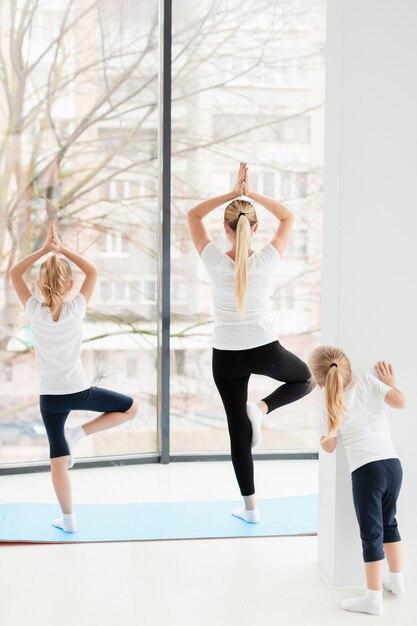 Rückansicht der Mutter in der Yoga-Pose mit Töchtern