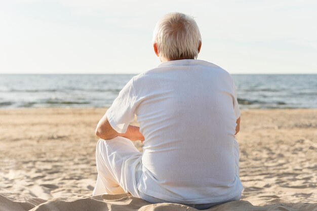 Rückansicht des älteren Mannes, der die Ansicht am Strand bewundert