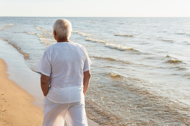 Rückansicht des älteren Mannes, der seine Zeit am Strand verbringt