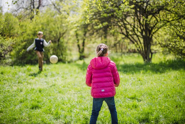 Rückansicht des Mädchens Fußball spielen mit ihrem Bruder