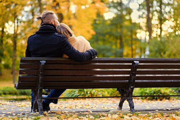 Rückansicht des Paares sitzt auf einer Bank in einem Herbstpark.