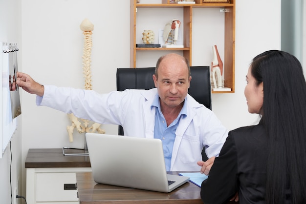 Rückansicht des Patienten beim Physiotherapeuten von Facharzt konsultiert