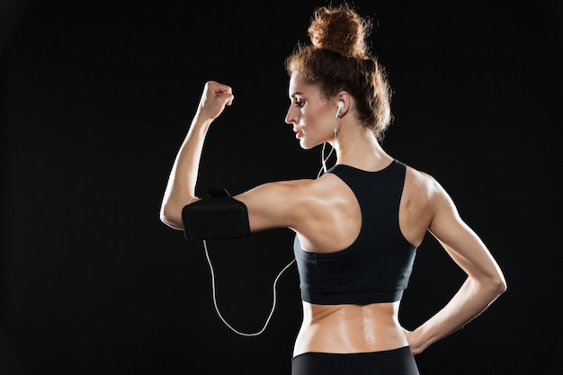 Rückansicht einer Fitnessfrau, die ihren Bizeps zeigt