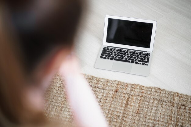 Rückansicht einer fitten Frau, die auf einer Matte sitzt, um ein Video auf dem Laptop anzusehen