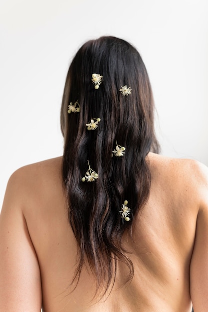 Rückansicht einer Frau, die nackt mit Blumen im Haar posiert