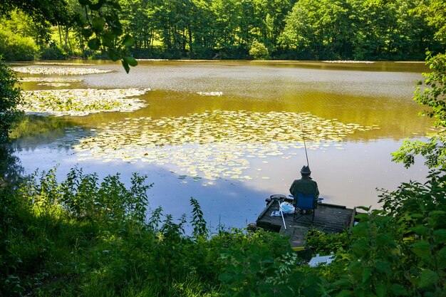 Rückansicht einer Person, die am frühen Morgen an einem See in Wiltshire, Großbritannien grob fischt