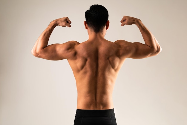 Rückansicht eines jungen Mannes, der seine Muskeln beugt und seinen muskulösen Rücken zeigt