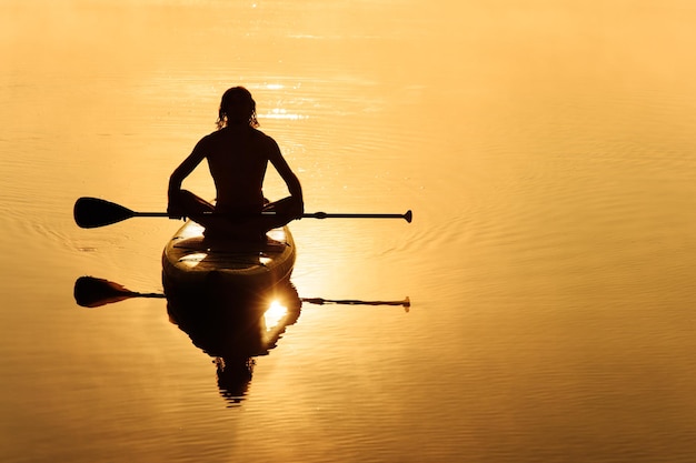 Kostenloses Foto rückansicht eines männlichen paddlers, der auf einem sup-board schwimmt