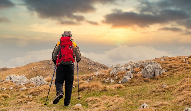 Rückansicht eines Wanderers, der den Sonnenuntergang von einem Berg aus beobachtet