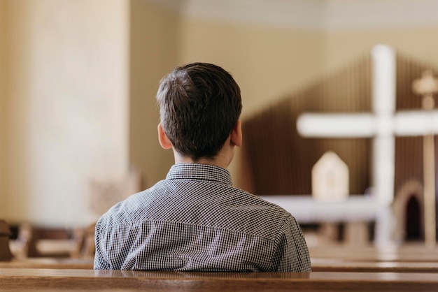 Rückansicht Junge, der in der Kirche betet