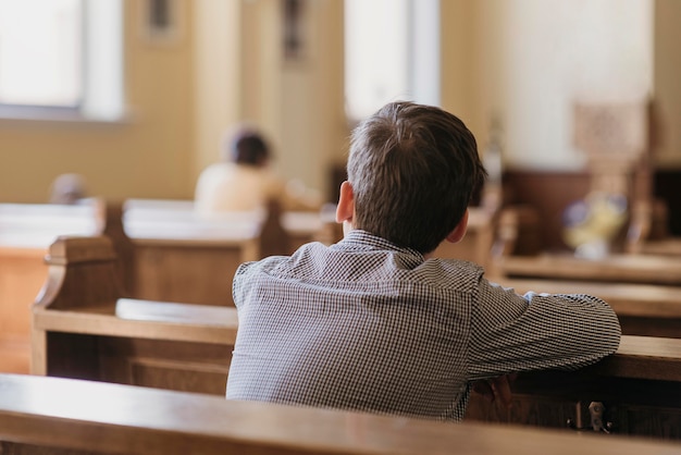 Kostenloses Foto rückansicht kleiner junge, der in der kirche betet