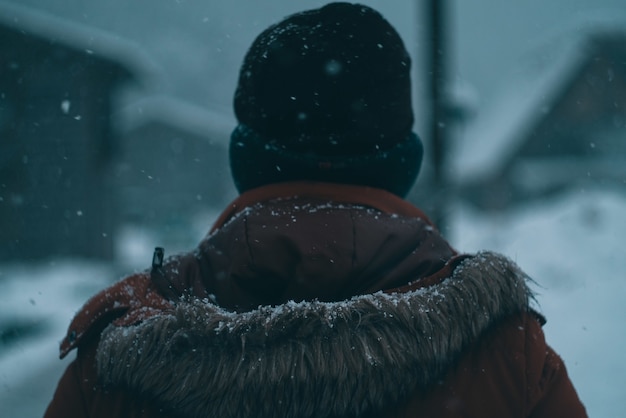 Rücken eines mannes mit kapuzenmantel und mütze im winter