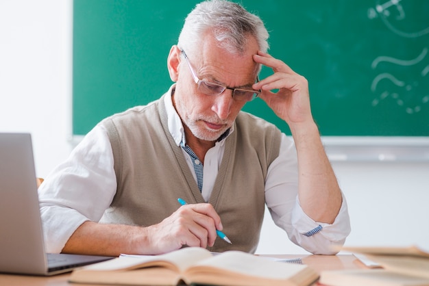 Rührender Tempel älteren Professors beim Behälter im Klassenzimmer