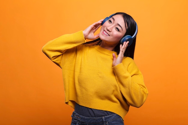 Ruhige, freundliche, süße asiatische person, die lieder auf audio-streaming-plattform mit drahtlosem headset hört. Entspannte Frau, die Kopfhörer trägt, während sie die Freizeit genießt, indem sie Musik hört.