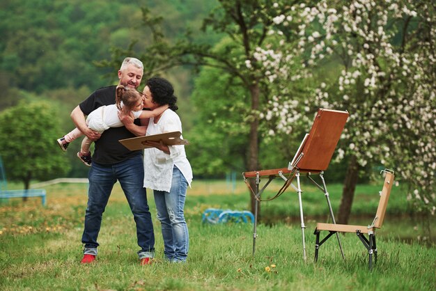 Ruhige und ruhige Atmosphäre. Großmutter und Großvater haben Spaß im Freien mit Enkelin. Malkonzeption