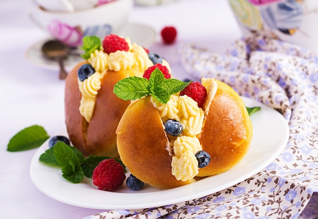 Rum savarian brötchen mit schlagsahne und frischen beeren dekoriert