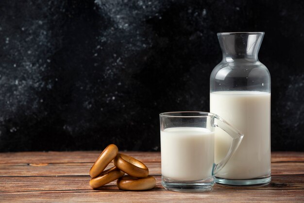 Runde Kekse, eine Flasche Milch und ein Glas Milch auf Holztisch.