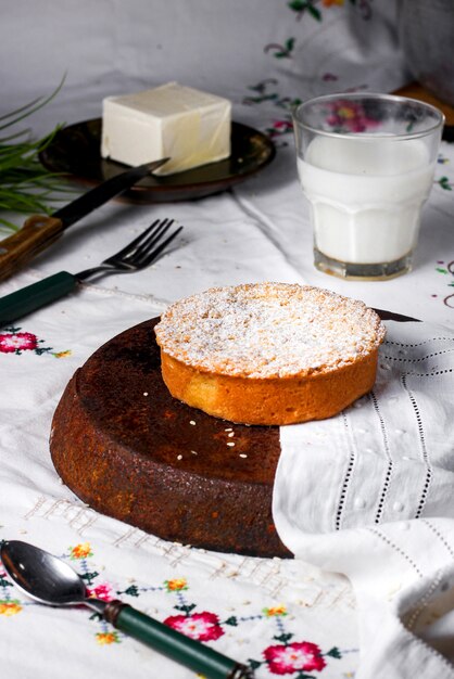 Runder Apfelkuchen mit Zuckerpulver bestreut, serviert mit Milch