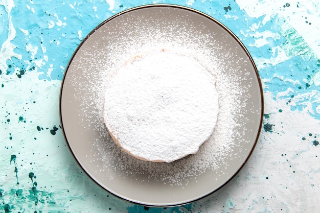 Runder Kuchen von oben mit Zuckerpulver im Inneren des Tellers auf der hellblauen Oberfläche