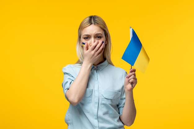 Russisch-ukrainischer Konflikt junges süßes Mädchen mit ukrainischer Flagge auf den Wangen, das mit Flagge weint