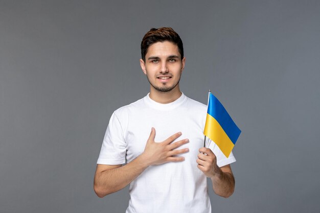Russischer Konflikt in der Ukraine hübscher süßer gutaussehender Mann im weißen Hemd mit den Händen auf der Brust glücklich