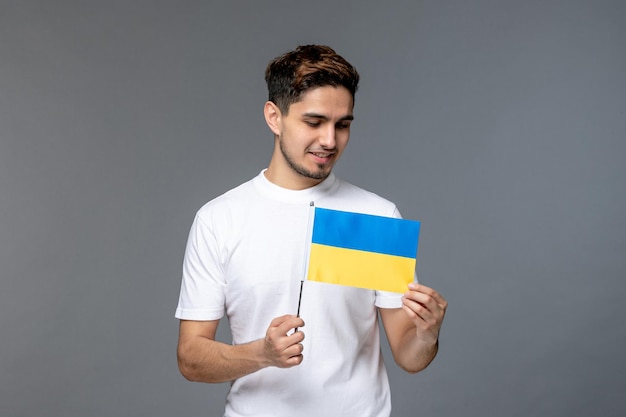 Russischer Konflikt in der Ukraine mutiger, süßer, gutaussehender Typ in weißem Hemd mit Blick auf die ukrainische Flagge