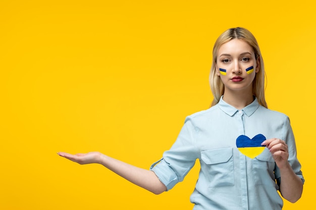 Russischer ukrainischer konflikt süßes mädchen gelber hintergrund mit ukrainischer flagge auf den wangen mit herz Premium Fotos