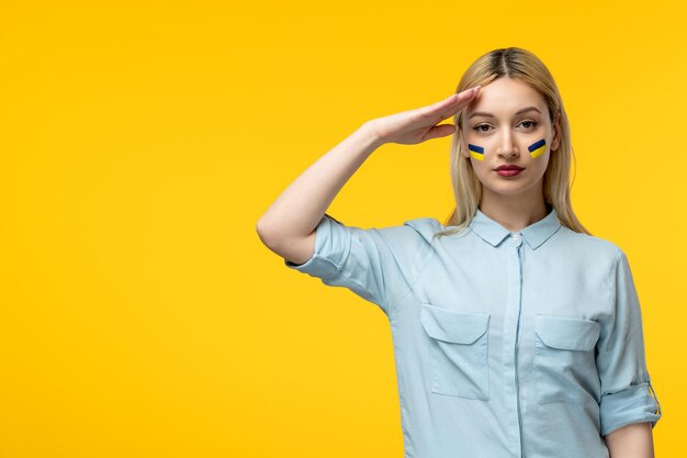 Russischer ukrainischer Konflikt süßes Mädchen gelber Hintergrund mit ukrainischer Flagge auf den Wangen