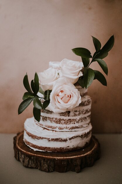 rustikale Hochzeitstorte mit drei weißen Rosen Topper auf braunem Textur Hintergrund