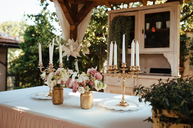 Rustikaler Kerzenständer und Blumenarrangement auf dem Tisch bei der Hochzeitsfeier.