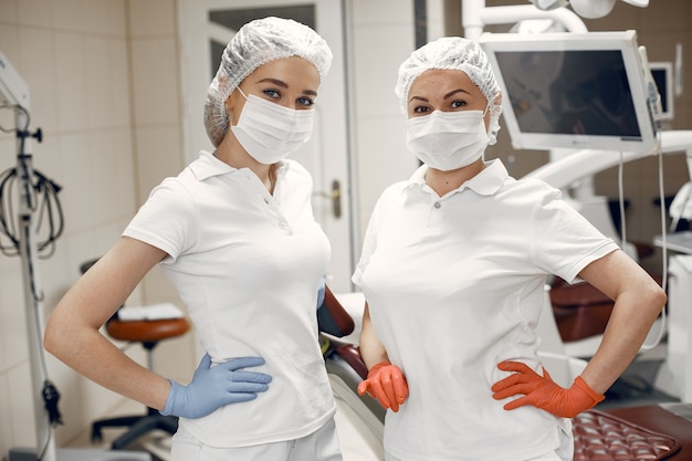 Ärzte in spezieller Uniform. Zahnärzte tragen Schutzmasken. Mädchen schauen in die Kamera