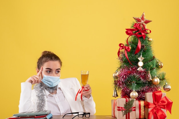 Ärztin der Vorderansicht in der Maske, die Weihnachten mit Champagner feiert